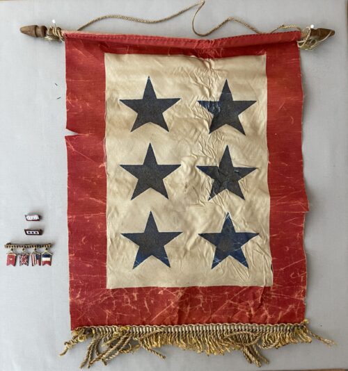 World War II–era service banner featuring six blue stars on a cream field, bordered in red with gold fringe and wooden hanging rod.