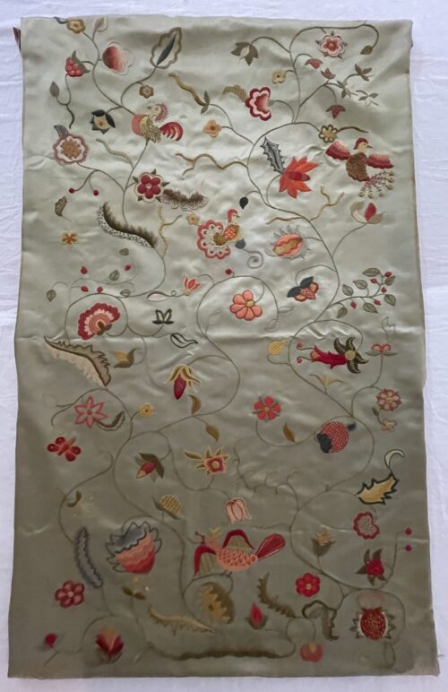 Aged antique silk embroidery with scrolling floral and bird motifs.