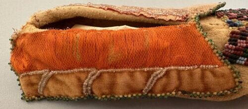 Native American slipper after treatment showing stabilized orange textile and beadwork.