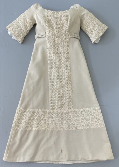 Wedding silk dress in cream color with lace panel and short sleeves after treatment, photographed flat against a neutral support.