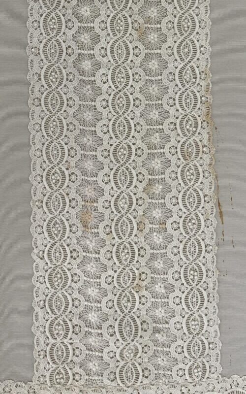 Wedding dress lace detail after treatment, photographed flat against a neutral support.