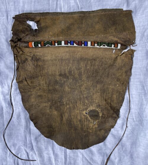 Women leather masai skirt with decorative beaded band before treatment, showing tears and descoloration.