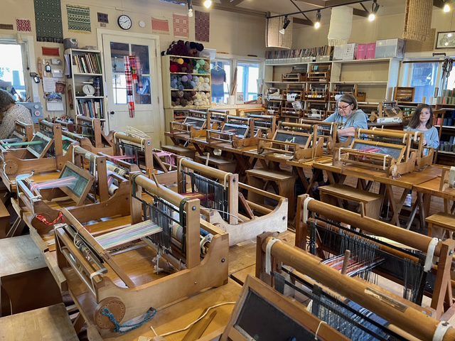 Weaving studio at the Little Loomhouse in Kentucky filled with wooden handlooms arranged in rows.