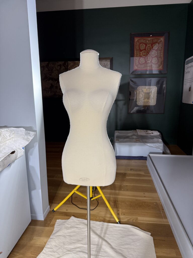 Standing female dress form torso and hips, covered in cream colored fabric.