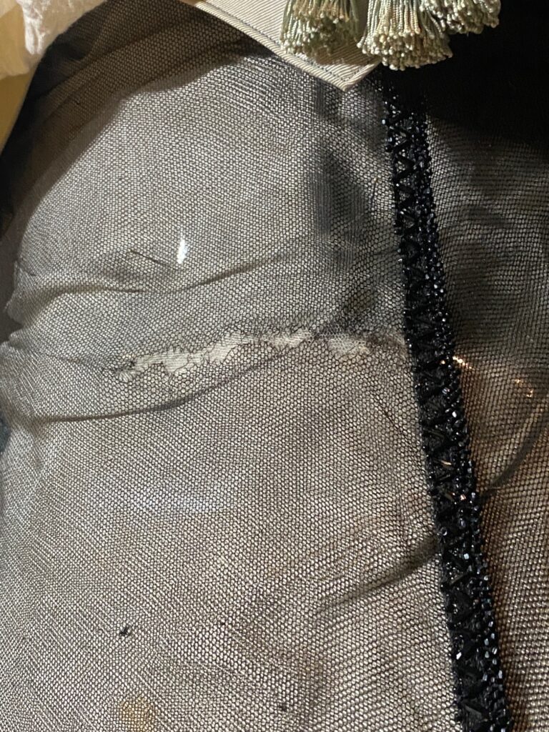 Close up of black netting with large white tear horizontally across the middle.