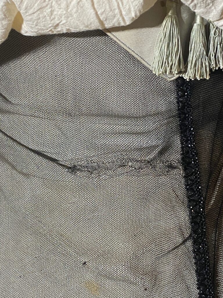 Close up of black netting showing rows of black stitching, repair to tear.