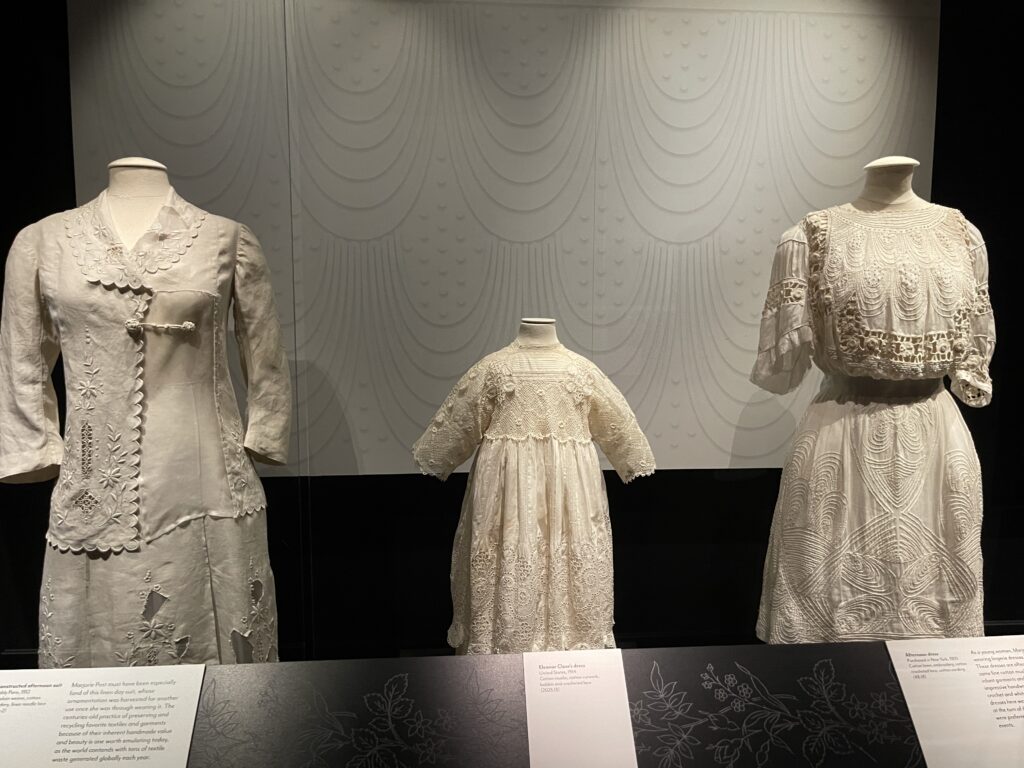 Display of three cream-colored lace cotton dresses shown standing on dress forms.