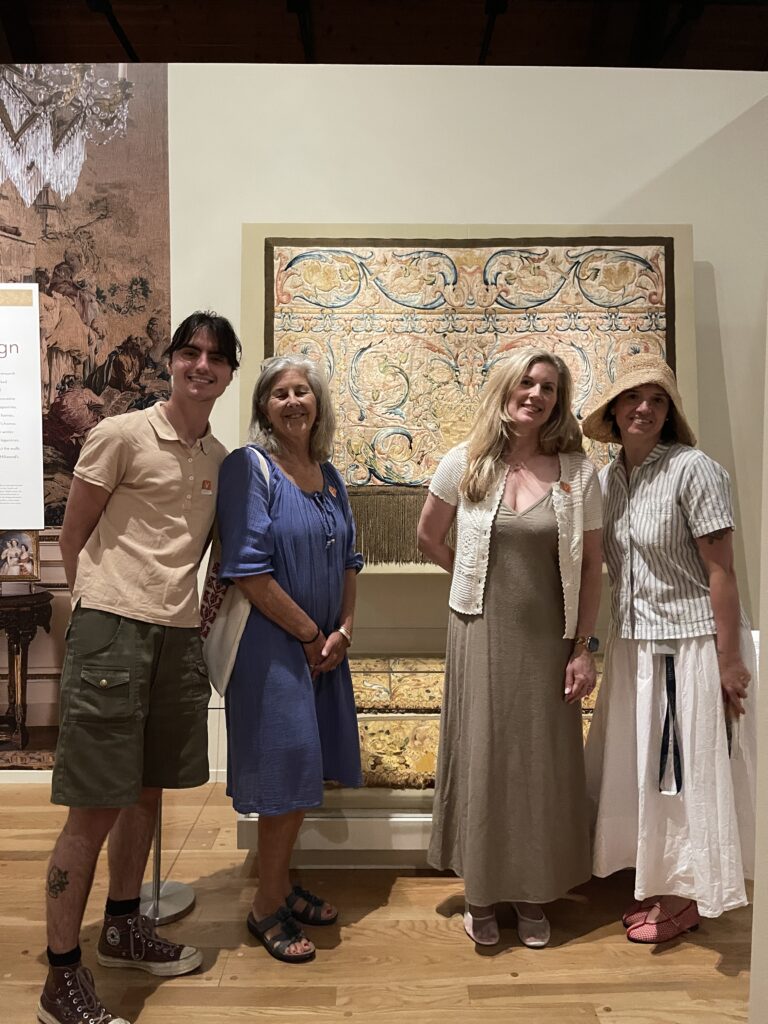 CFT team: Young man and three women stand in front of yellow colored textile embroideries