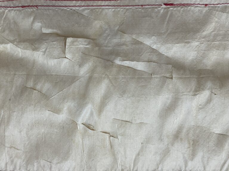Close up of white silk with many tears and splits.