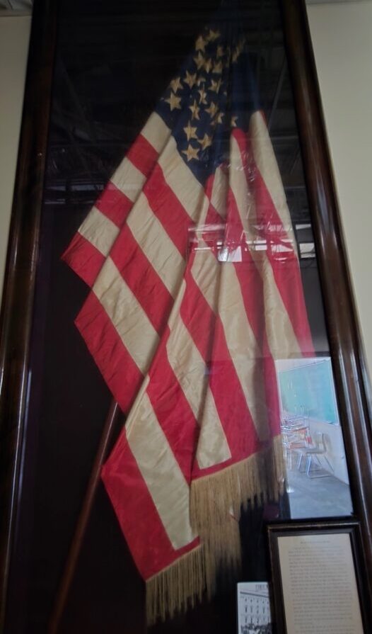 35-Star Barbourville Home Guard flag hanging in folds vertically, in a dark case