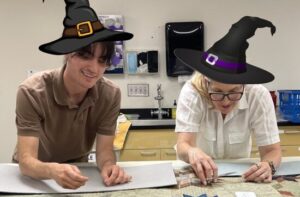 Caring for Textiles staff sewing while wearing witch hats.
