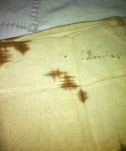 Frederick Douglass damaged and aged handkerchief before restoration with the name Douglass written in upper right corner.