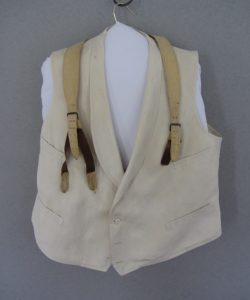 Frederick Douglass light beige waistcoat and tan suspenders placed on a hangar after restoration.