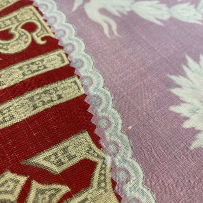Close up of pale white sheer cloth and red and cream-colored printed cloth handkerchief.