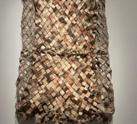 Woven textile artwork composed of interlaced fabric strips.