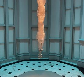 A glowing, translucent fiber sculpture hangs suspended in a curved gallery alcove.