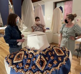 A beaded navy garment from Princess Grace Kelly's collection displayed on a mannequin during exhibition installation.