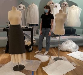 Conservator stands between two dress forms during installation of Princess Grace Kelly’s garments.