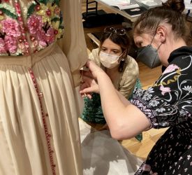 Two textile conservators adjusting the fit of an embroidered gown worn by Princess Grace Kelly prior exhibition.