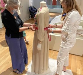 Julia and her colleague fitting a belted gown worn by Princess Grace Kelly onto a mannequin for exhibition.